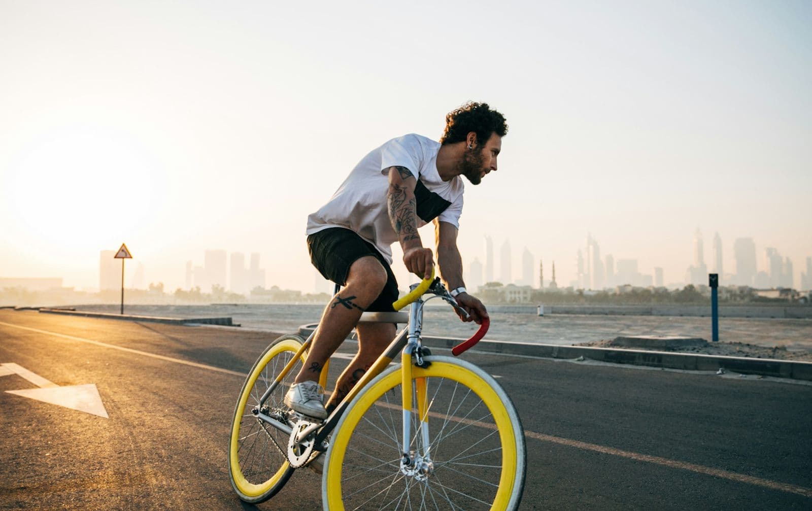 A cyclist riding along a coastal road at sunrise