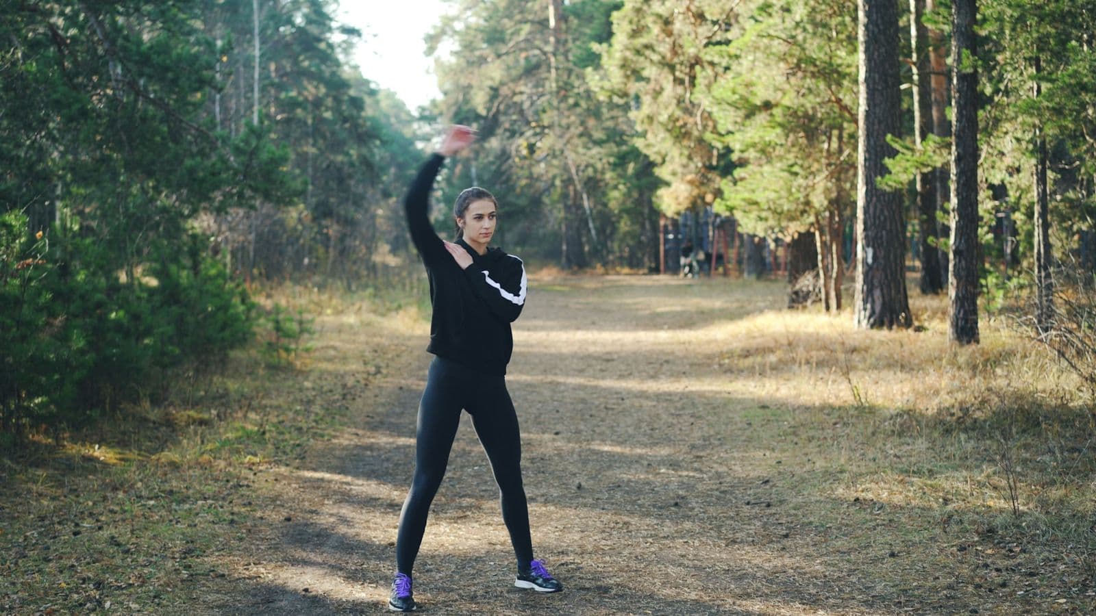 A woman stretching on a forest path