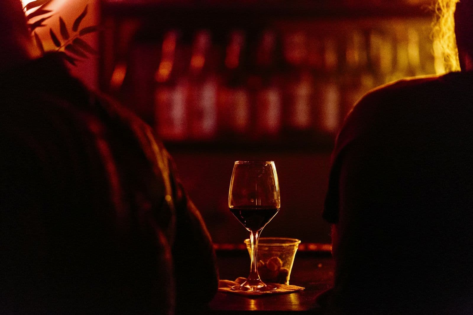 A glass of red wine on a table in a dim bar